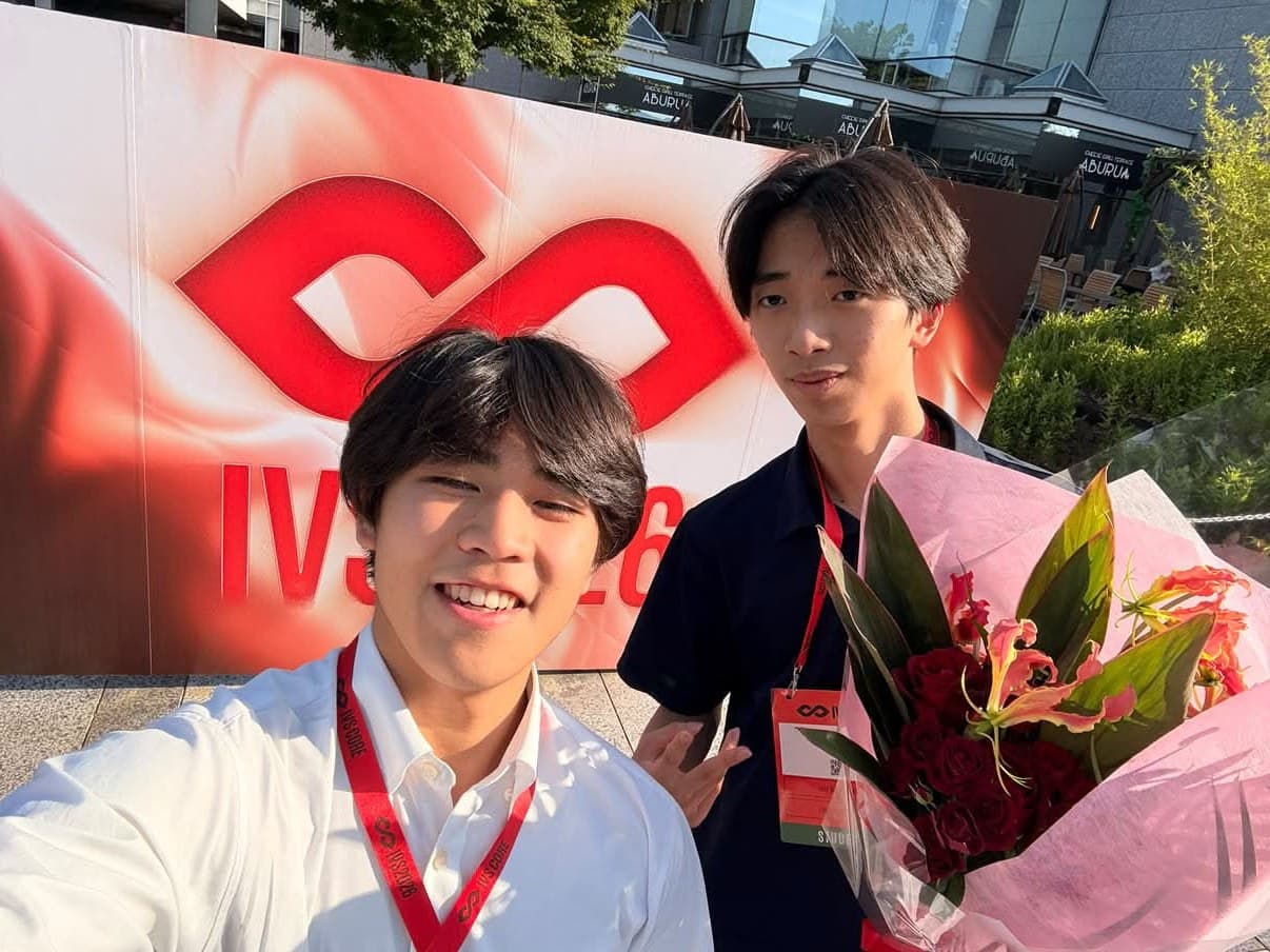 IVS2026の会場前で、花束を手にしたBlescのメンバー2人
